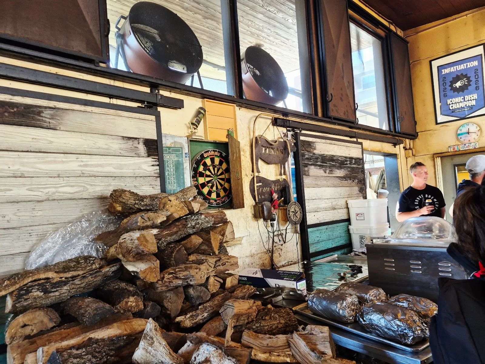 Stacked wood, dartboard, and smoked meat prep.