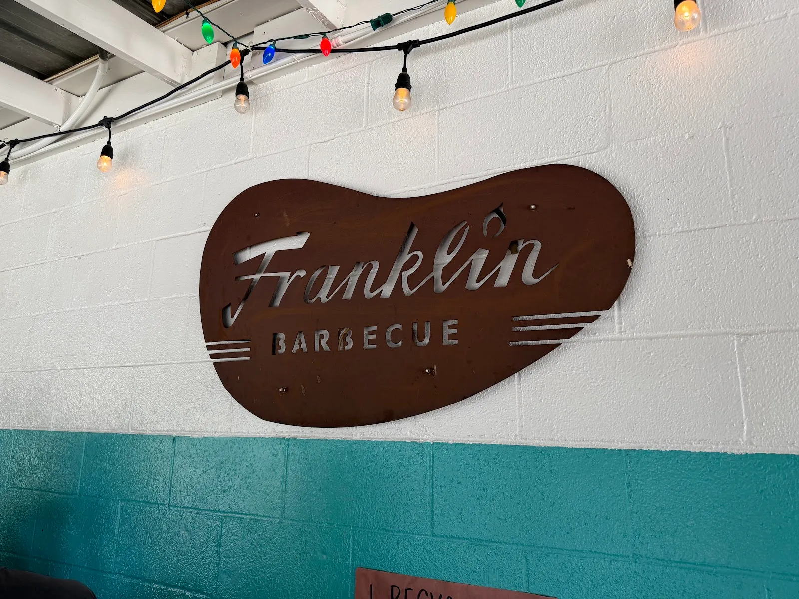Weathered Franklin Barbecue sign with festive lights.