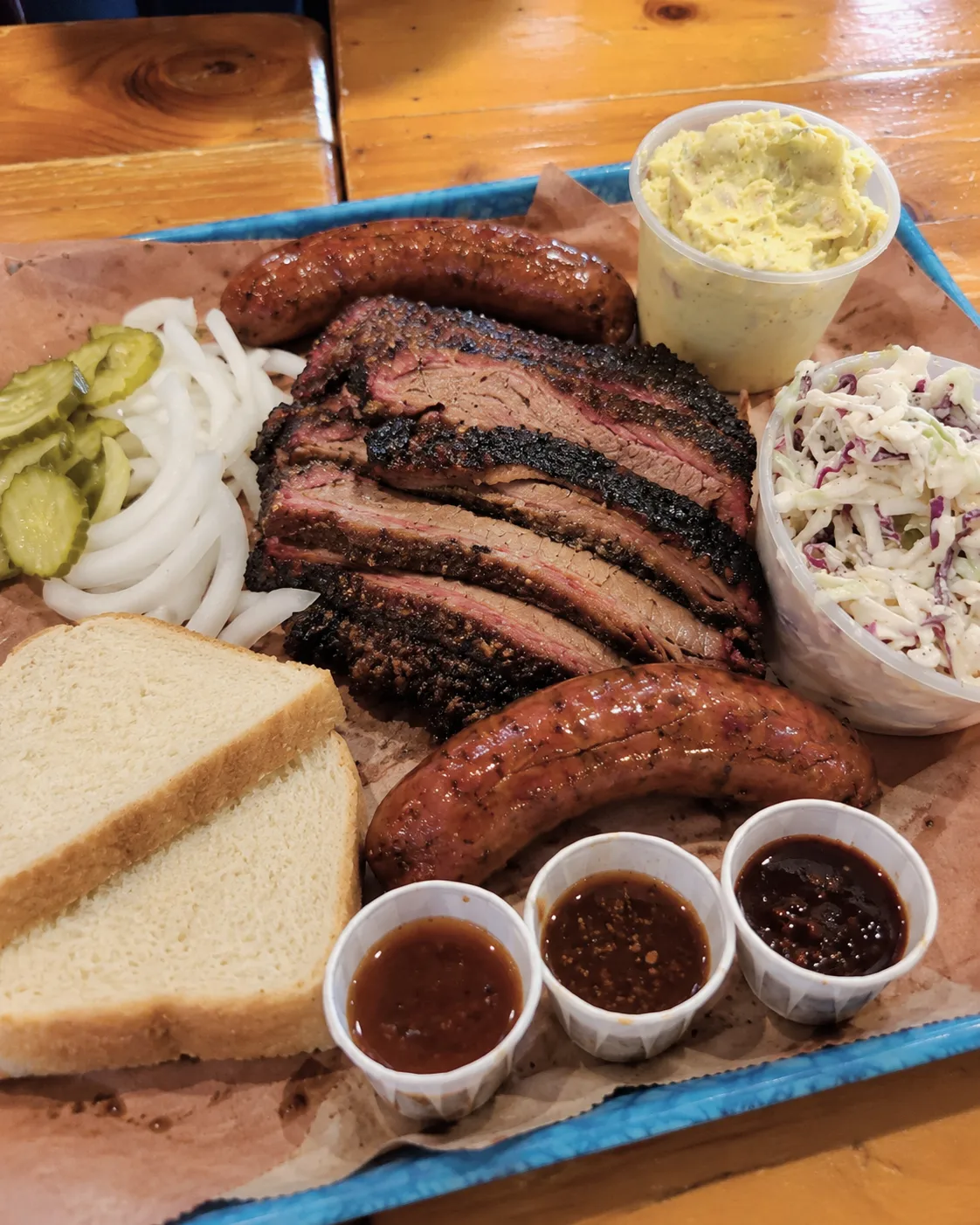 Generous barbecue platter: brisket, sausage, sides, and sauces.