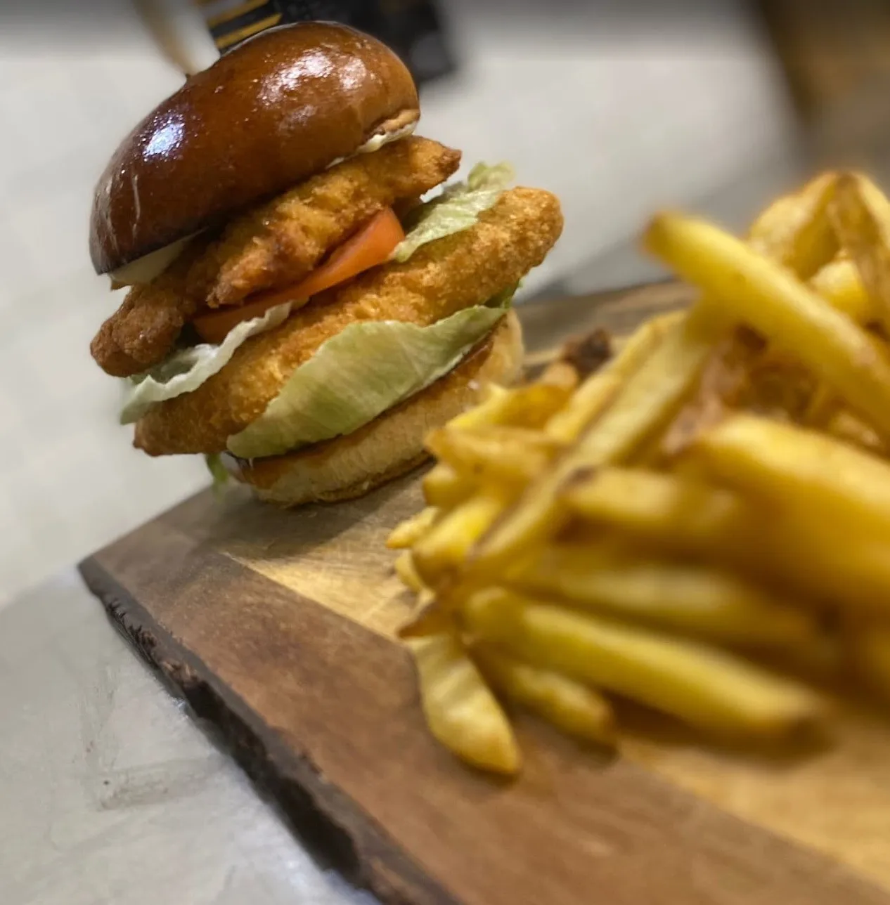 Křupavý kuřecí burger s čerstvou zeleninou a hranolky.