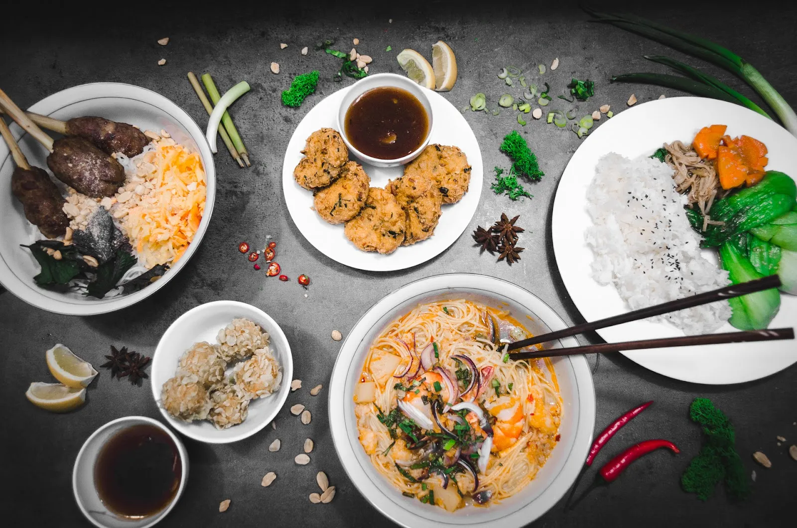 Pestrá hostina vietnamských specialit na tmavém pozadí.
