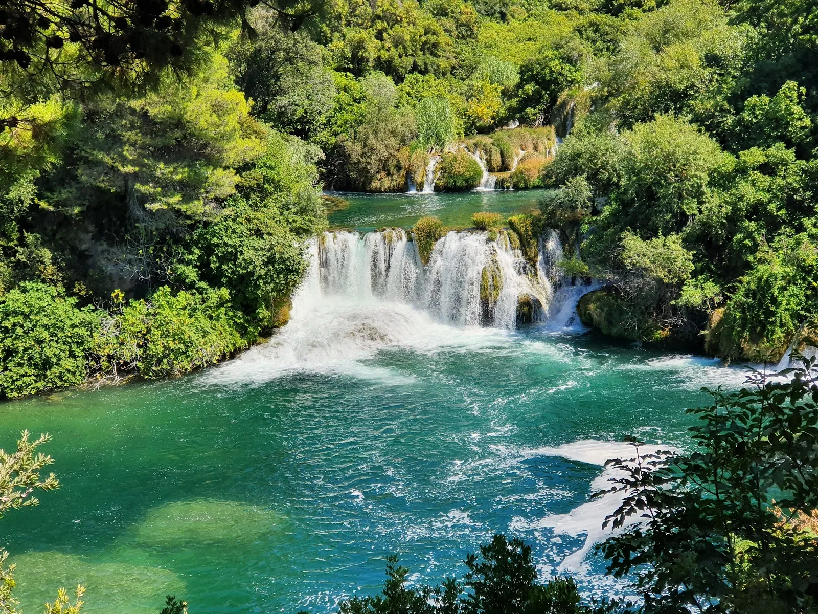 Stunning turquoise waterfalls cascade through lush greenery