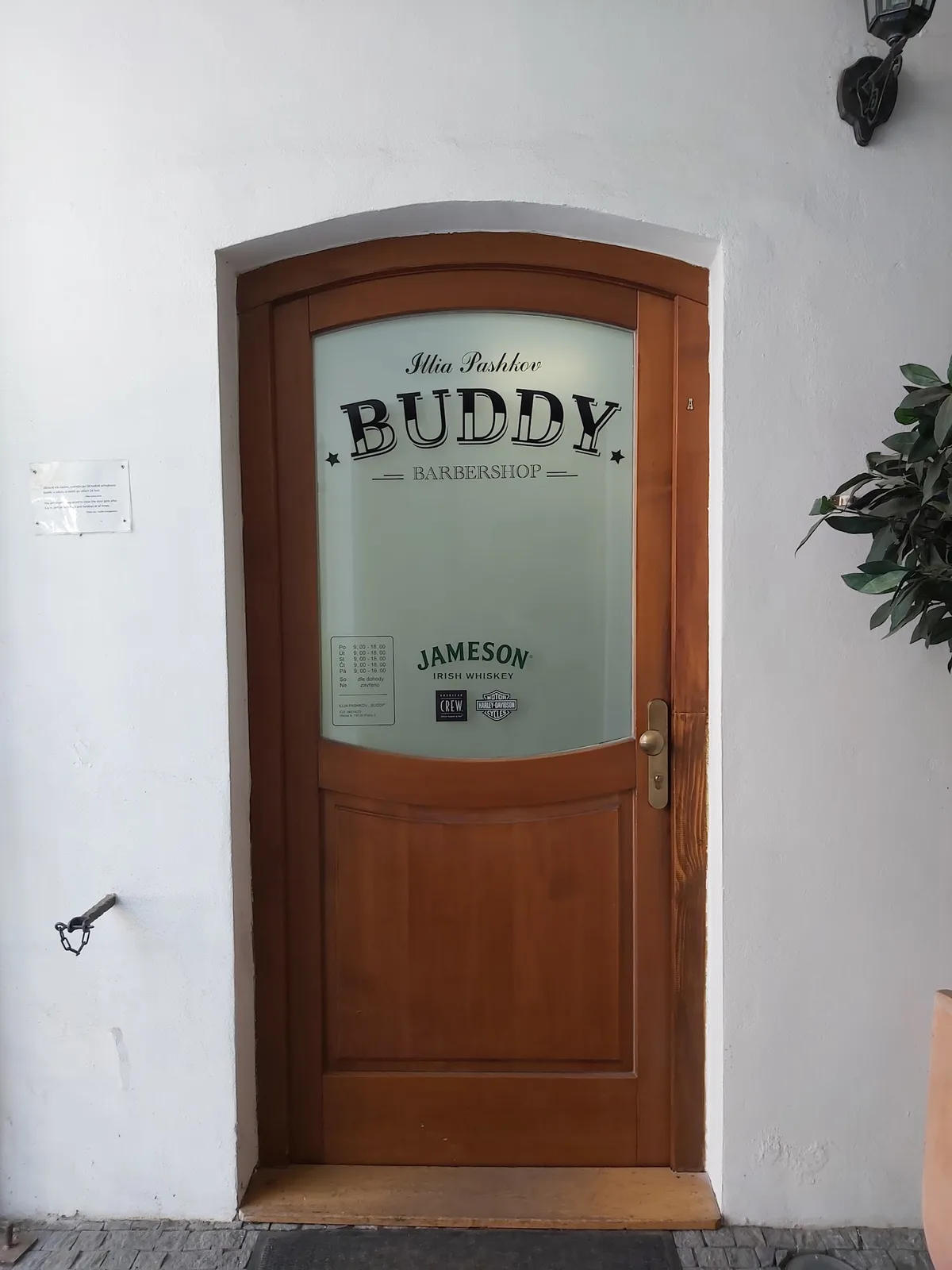 Stylové dřevěné dveře s logem BUDDY Barbershop Žižkov.