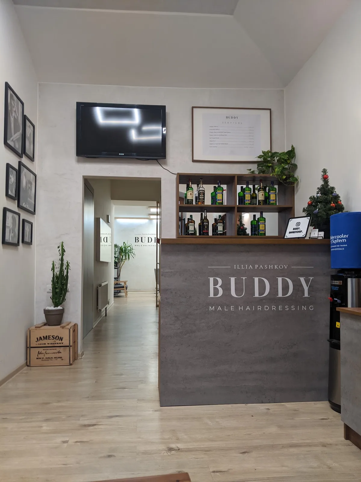 Elegantní recepce BUDDY Male Hairdressing s nabídkou nápojů.