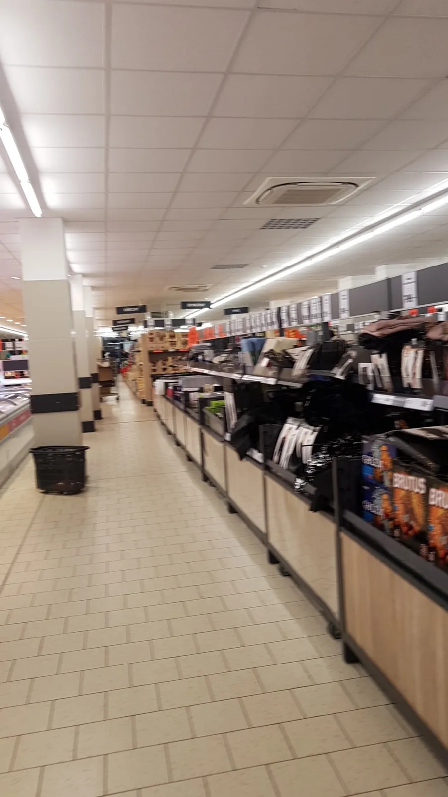 Široká ulička s regály plnými rozmanitého zboží.