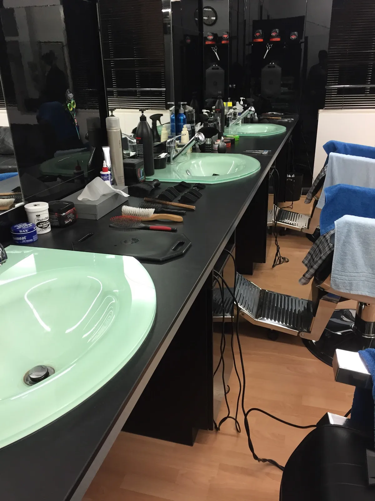 Sleek barber stations, modern green sinks, professional grooming tools.