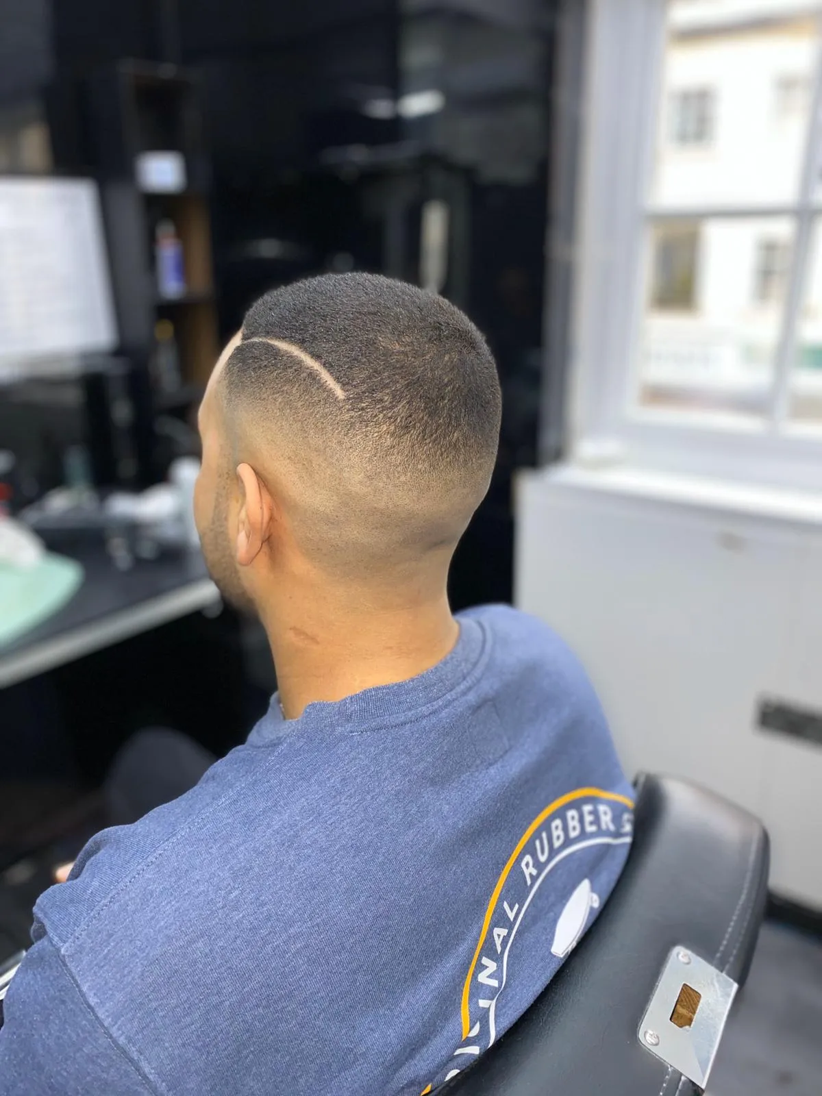 Fresh fade haircut with unique shaved line design.