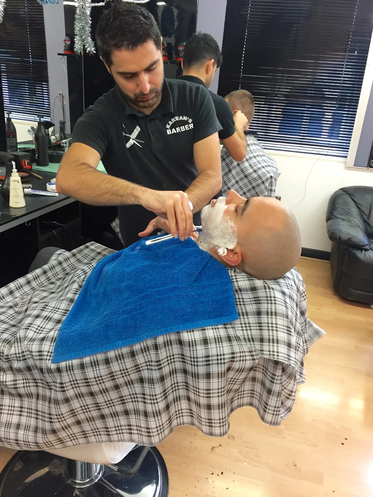 Professional barber providing a traditional straight razor shave.