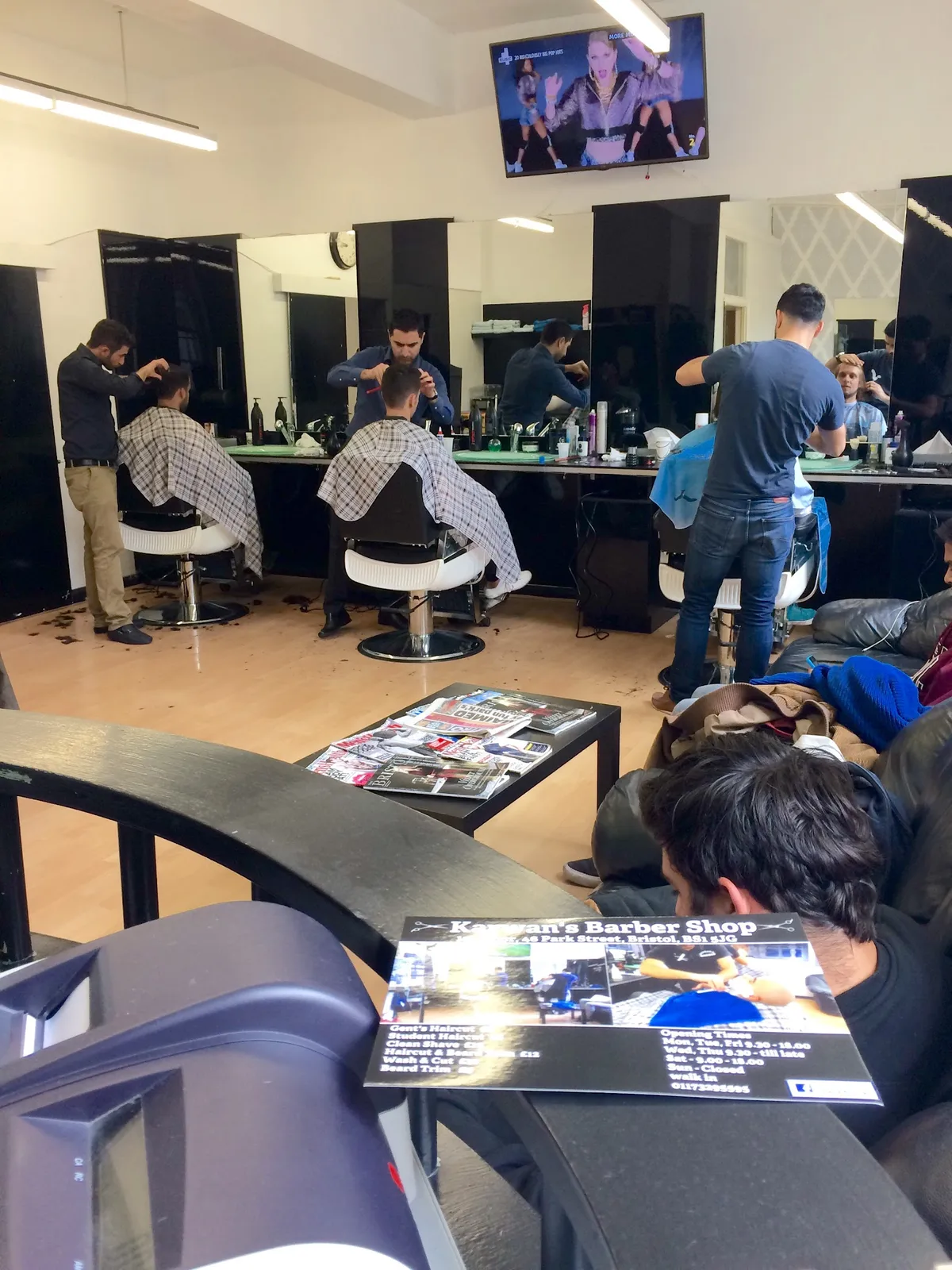 Lively barber shop, skilled stylists at work.