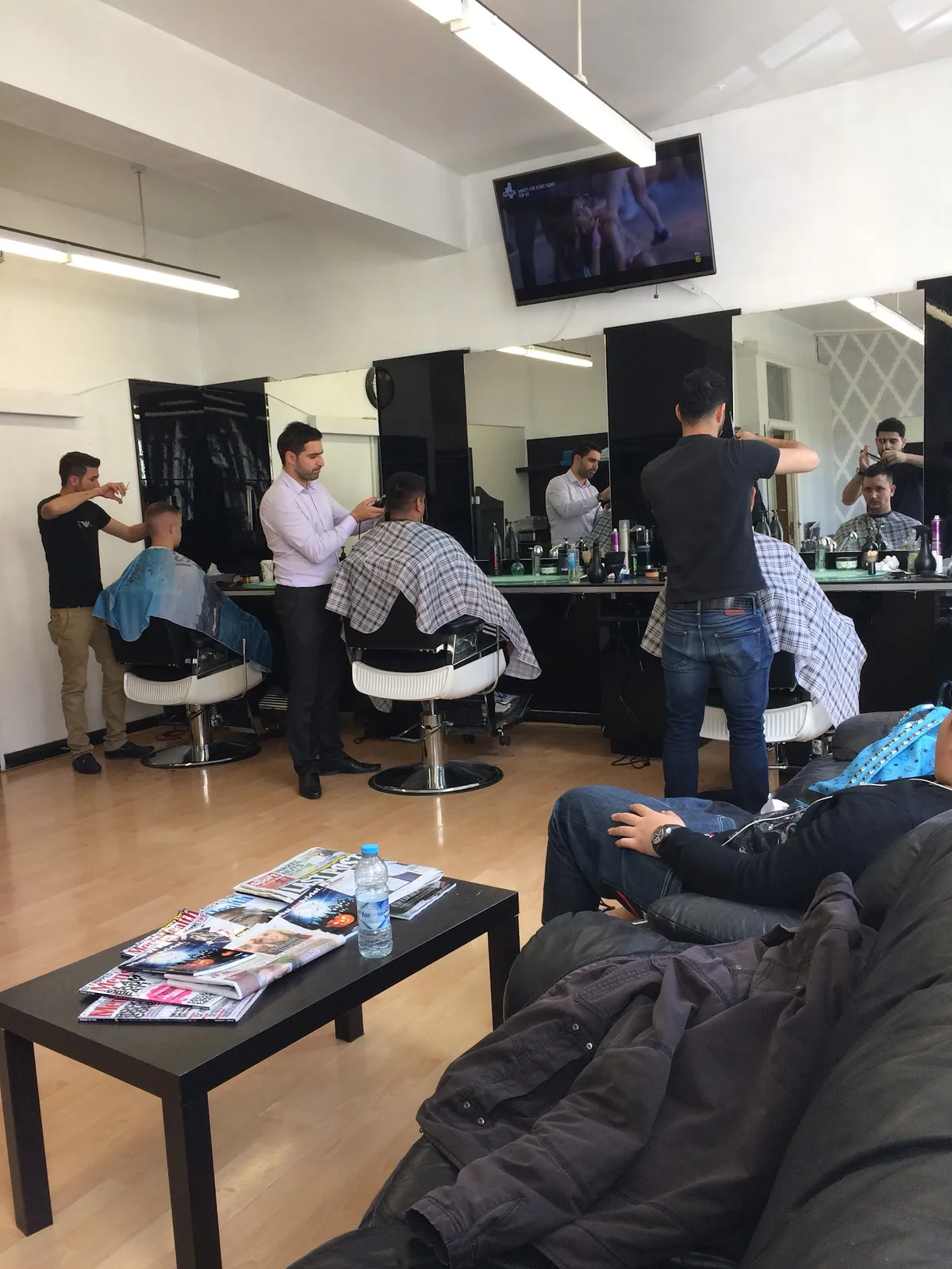 Busy barbershop interior with multiple stylists working.