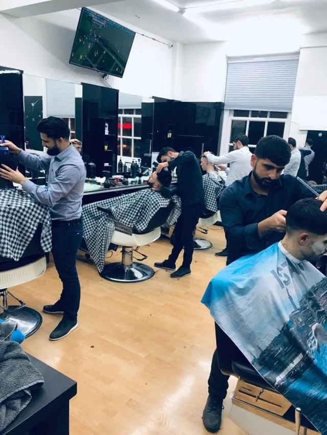 Lively barbershop scene with multiple stylists expertly cutting hair.