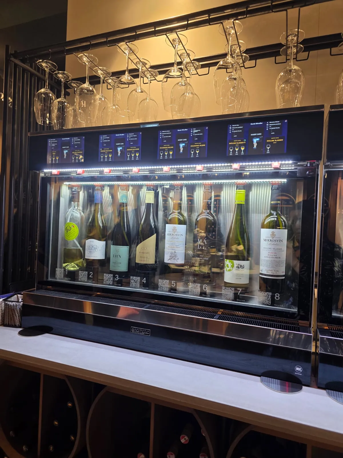 Moderní vinný automat s osmi lahvemi vína.
