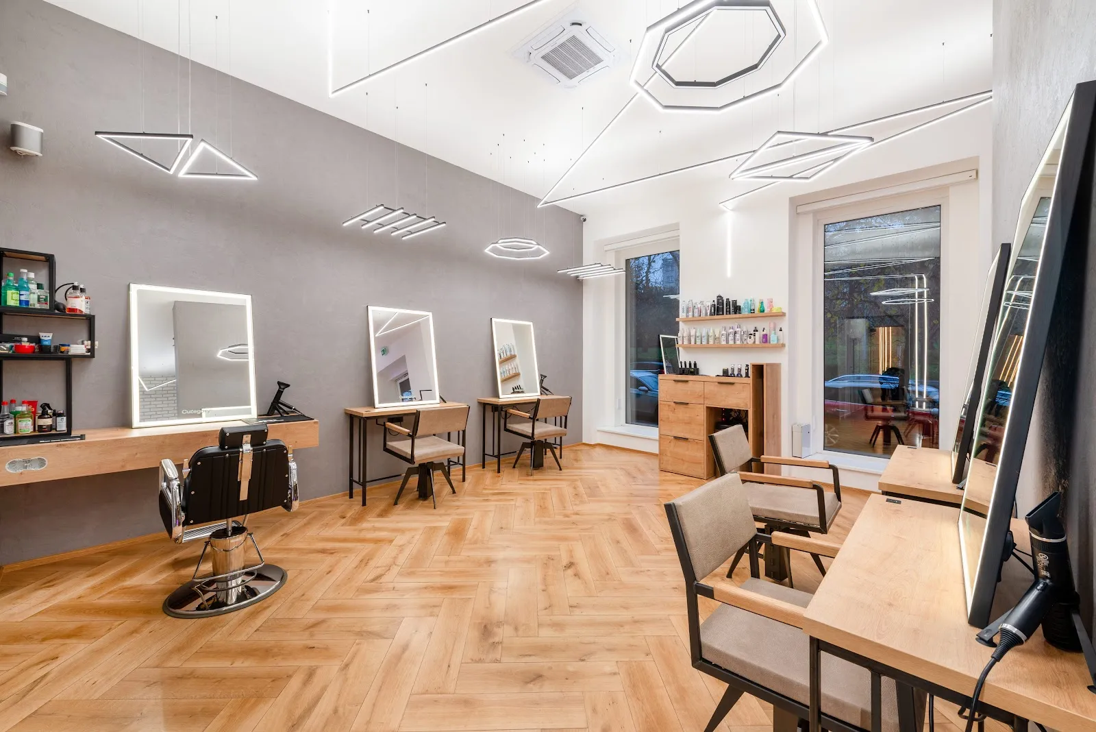 Moderní kadeřnictví s geometrickým osvětlením a dřevěnou podlahou.